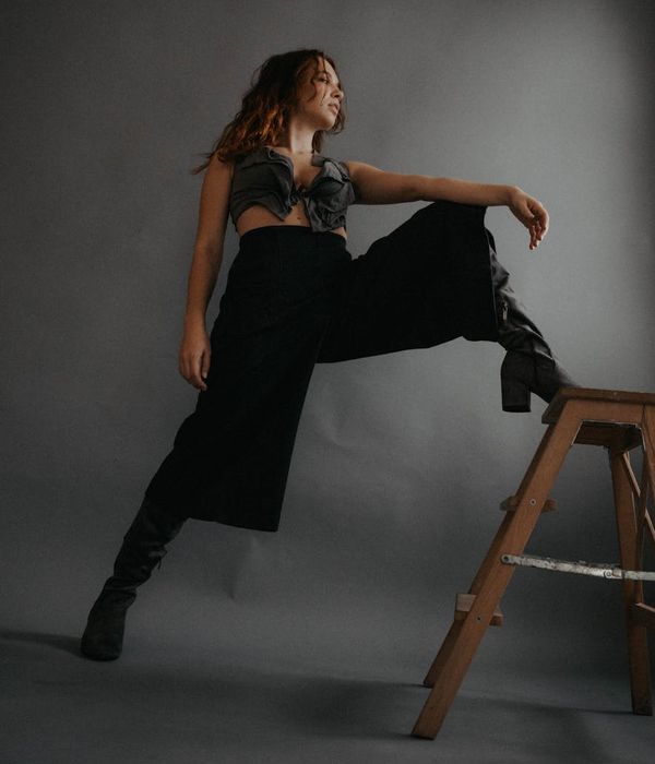 Woman standing confidently with a balanced posture against a steel grey background.